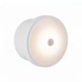 Round white LED motion sensor night light on a white background, shown from a 3/4 angle