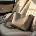 Lifestyle photo of the taupe tote bag on a cream leather car seat